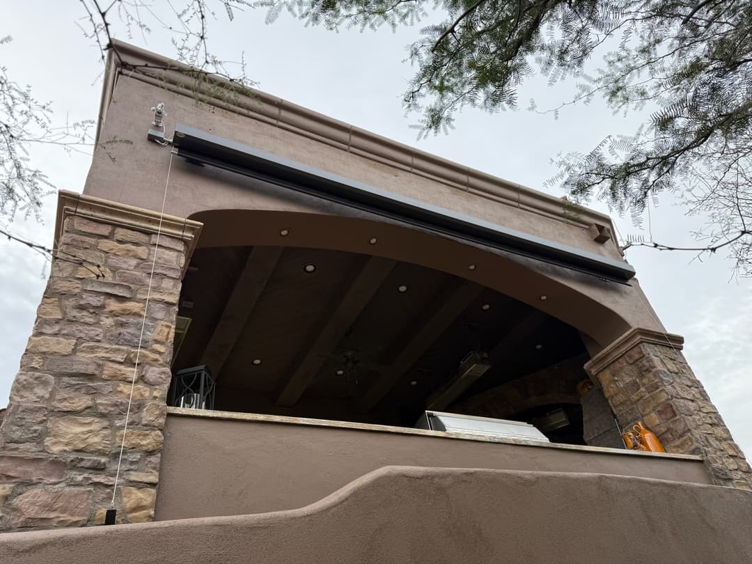 Tall cable-guided exterior shade mounted above a Phoenix outdoor kitchen