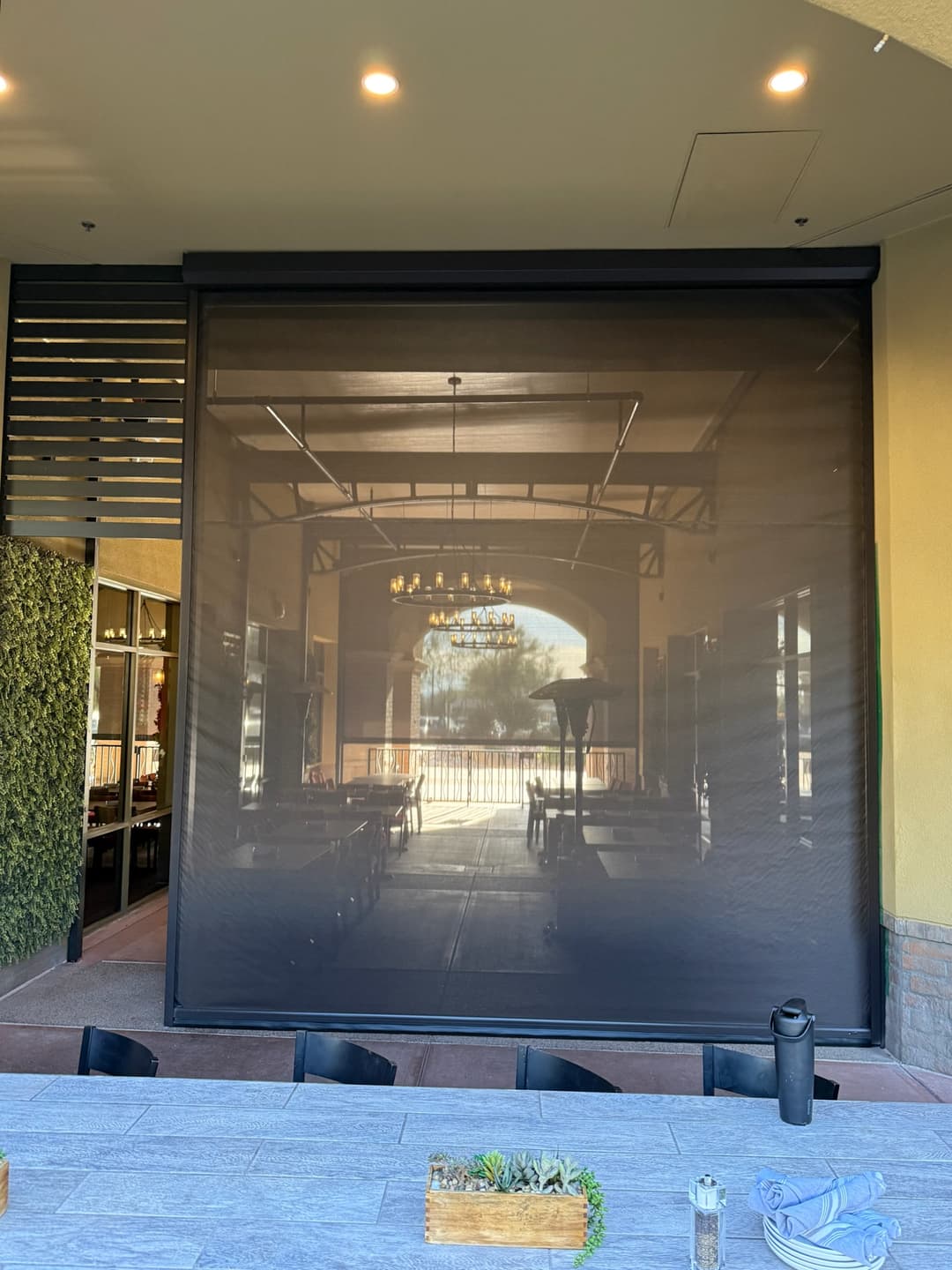 A large exterior drop shade protecting patio dining in a breezeway in Phoenix AZ