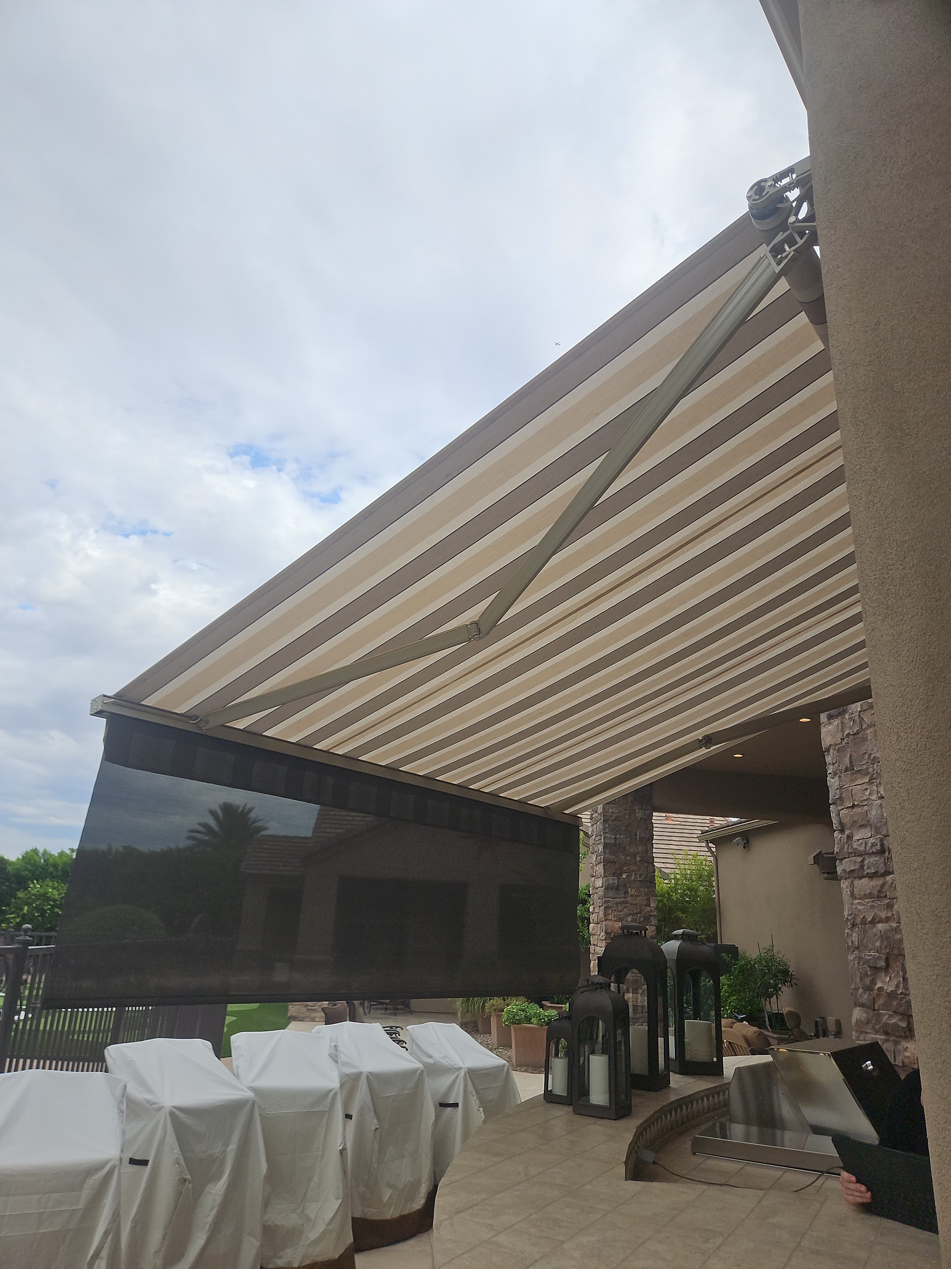 Restored striped retractable awning with an integrated front-bar drop shade