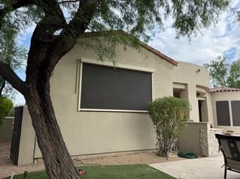Black exterior window shade with tan hardware on a Phoenix home