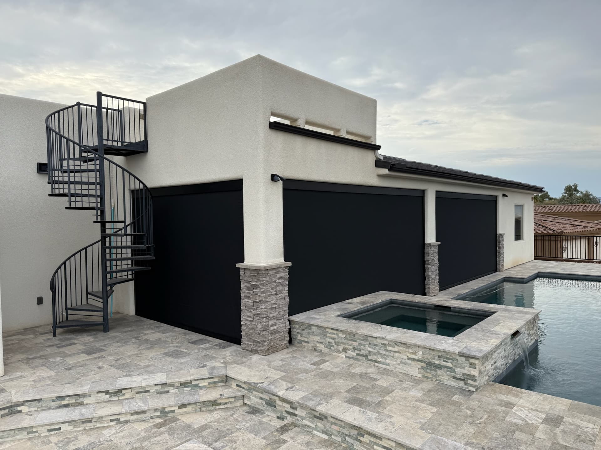 Track-guided exterior shades lowered across a residential patio